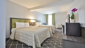 Une chambre d’hôtel avec deux lits, un bureau, une télévision et une plante.