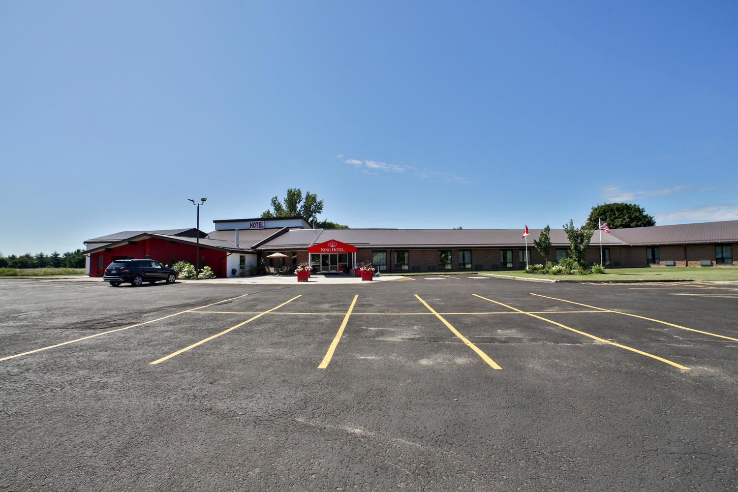 A hotel with a parking lot, a red building, and a sign that reads "King Hotel".