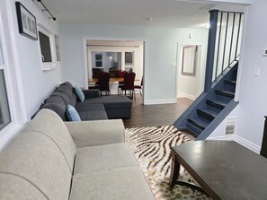 A living room with a sectional sofa, a coffee table, and a staircase.