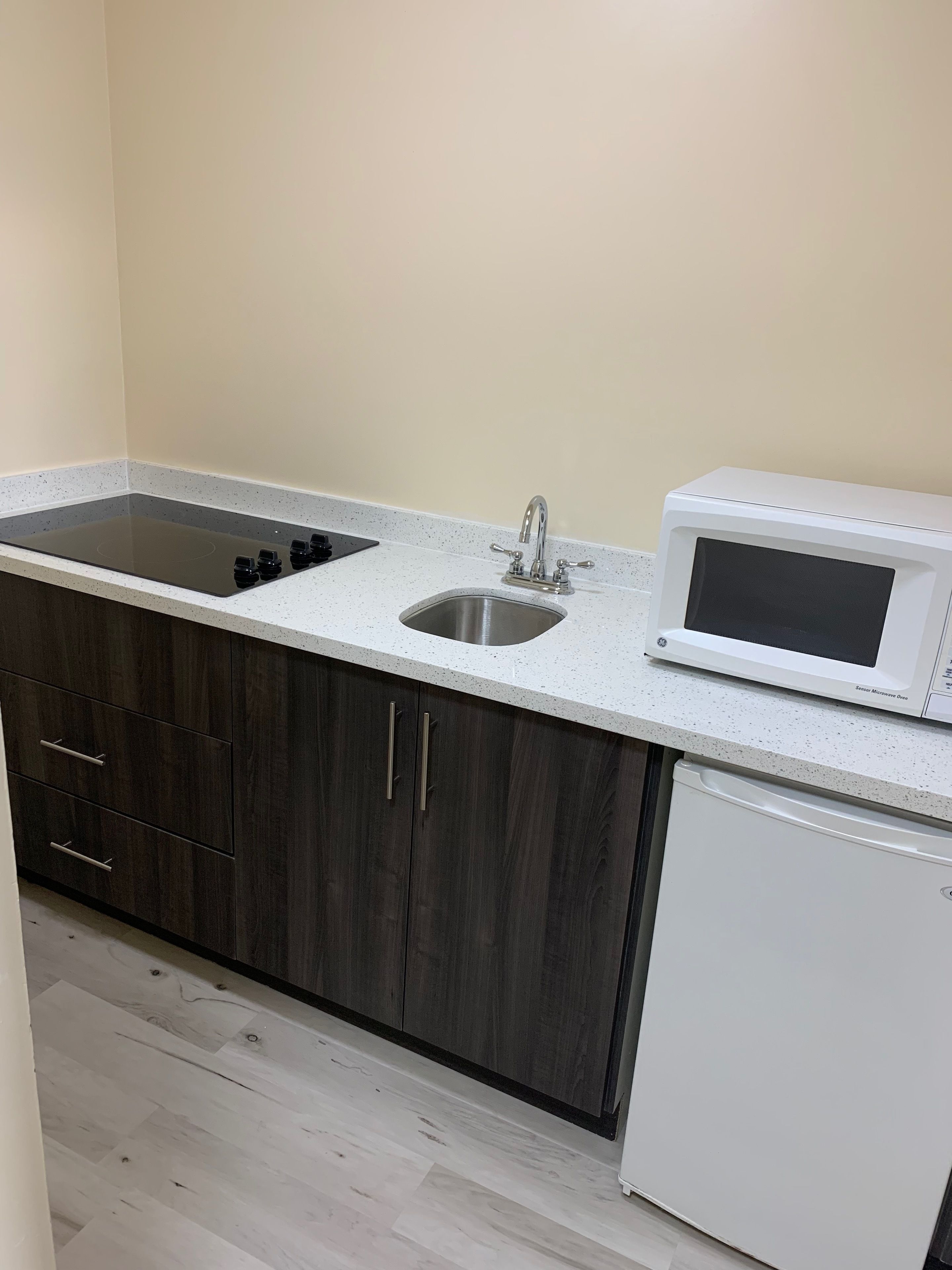A compact kitchen with a built-in stovetop, a sink, and a microwave.