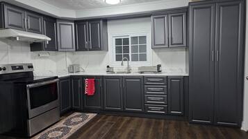Una cocina con armarios oscuros, una estufa de acero inoxidable, una ventana y un tapete estampado.