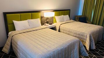 A hotel room with two beds, a nightstand, a lamp, and a patterned floor.
