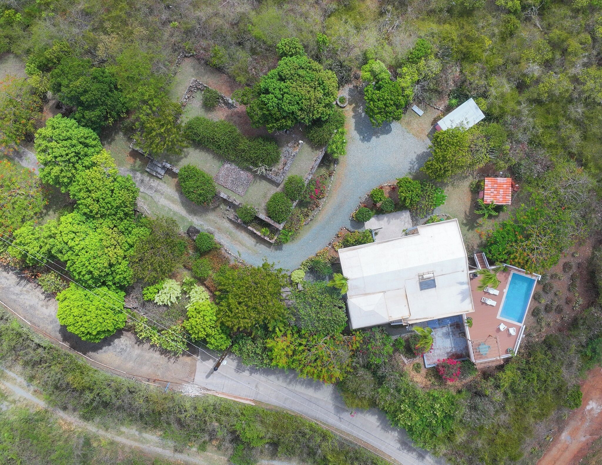 Vue aérienne d’une propriété comprenant une piscine, une grande maison et un espace verdoyant.