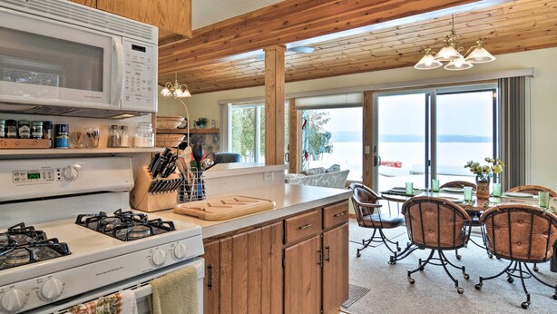 A kitchen with a stove, microwave, and wooden cabinets. There is a dining area with a table and chairs.