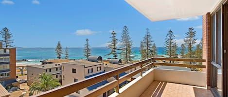 Ein Balkon mit Blick auf den Ozean und die umliegenden Gebäude.