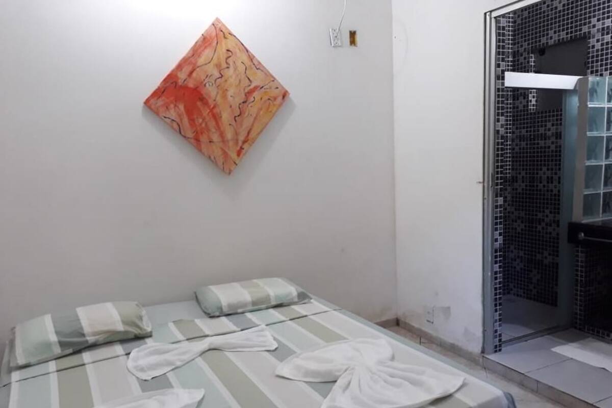 Une chambre d’hôtel avec un lit, une œuvre d’art accrochée au mur et une douche carrelée.