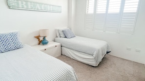 A bedroom with two beds, a nightstand, a lamp, and a window with blinds. - Tasman Towers 22, 3 Munster Street, Port Macquarie (Port Macquarie)