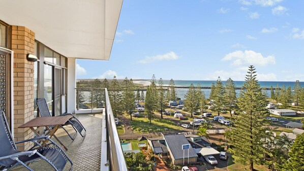 A balcony with a view of a beach and parked vehicles. - Tasman Towers 22, 3 Munster Street, Port Macquarie (Port Macquarie)
