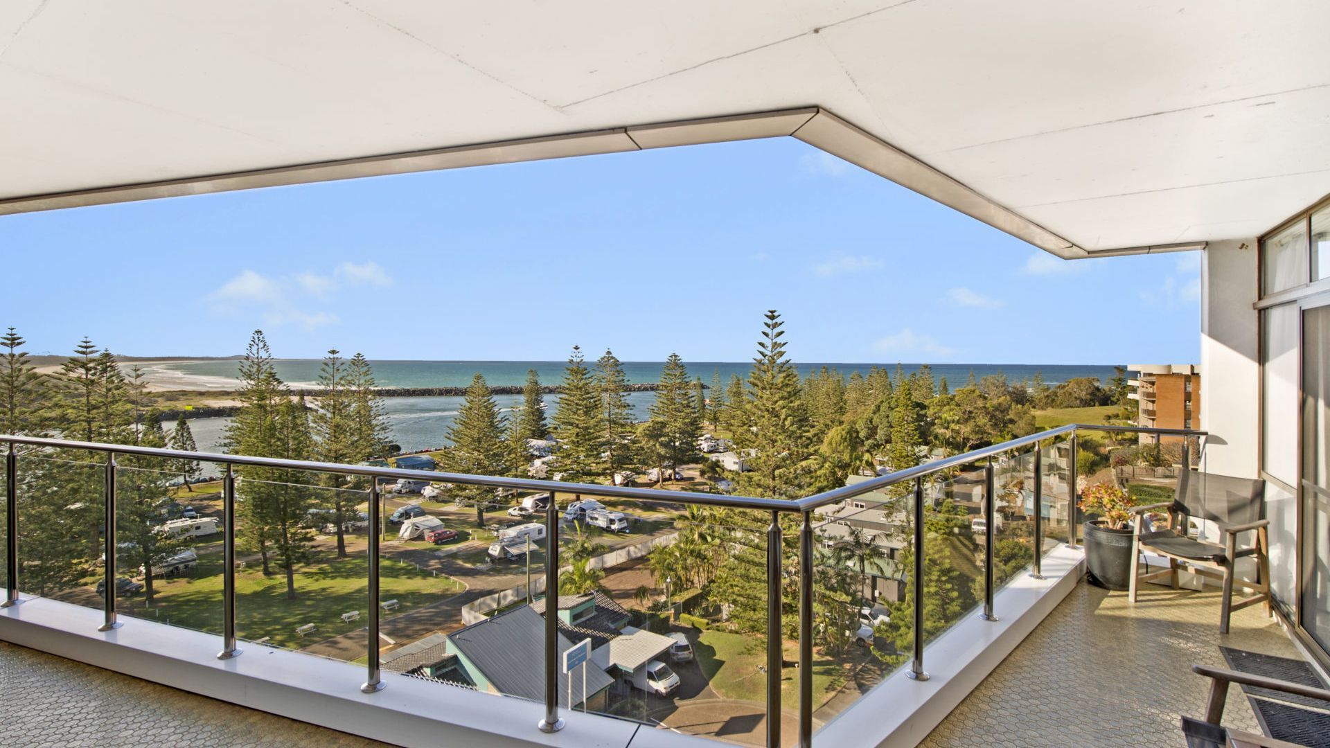 Ein Balkon mit Blick auf Strand und Meer, mit Metallgeländern und blauem Himmel.