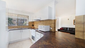 Cocina moderna con armarios blancos, un microondas y un ventanal con vistas a edificios.