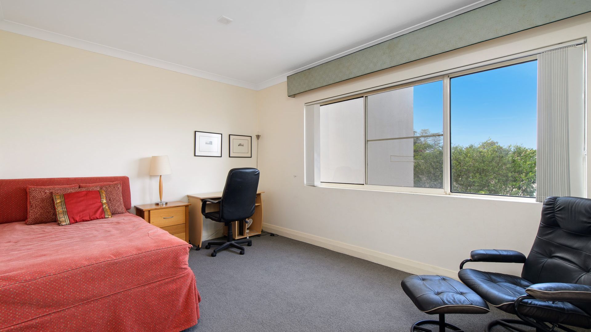 A hotel room with a bed, a desk, a chair, and a large window.
