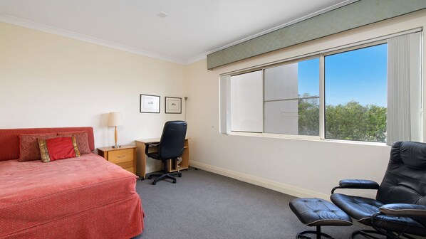 A hotel room with a bed, a desk, a chair, and a large window.