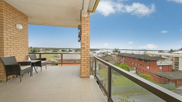 A balcony with a view of a parking lot and buildings.