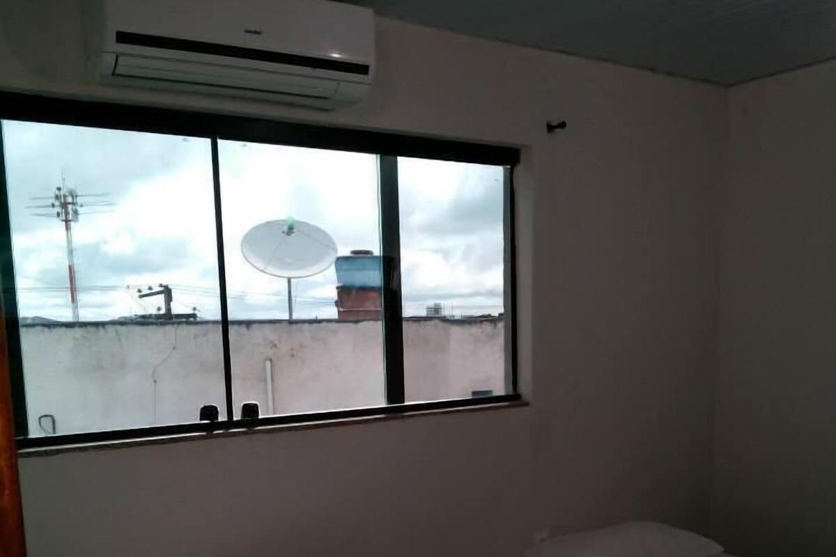 Quarto com duas camas de solteiro, janela com vista para o exterior e ar condicionado sobre a janela.