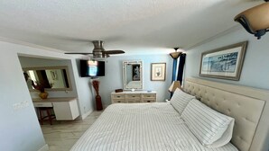 A bedroom with a large bed, a dresser, a vanity, a ceiling fan, and a television. - 3BR Waterfront Oasis w/ Private Solar Heated Pool and Spacious Deck (Holiday)