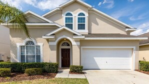 A single-story house with a beige facade, a brown front door, and a white garage door.
