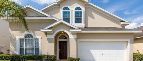 A single-story house with a beige facade, a brown front door, and a white garage door.
