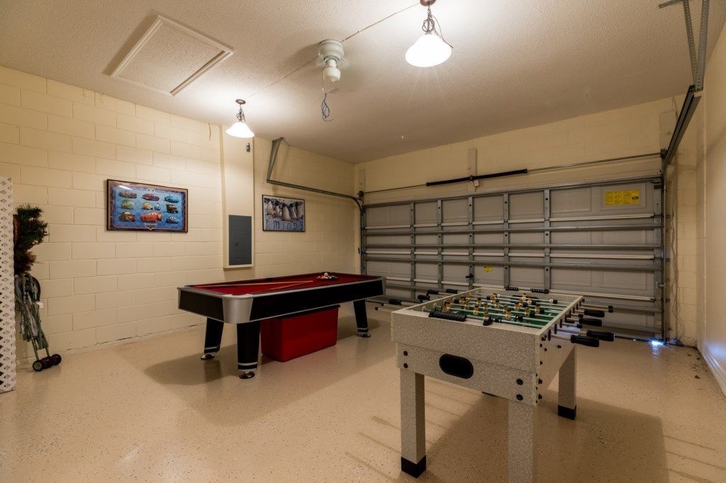 A recreational room with a pool table, foosball table, and a garage door.