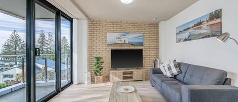 Un salon moderne avec un téléviseur à écran plat, un canapé gris et une table basse en bois.