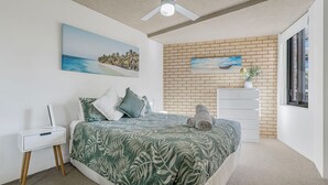 A bedroom with a bed, a nightstand, a dresser, and a window. - Tasman Towers 5, 3 Munster Street (Port Macquarie)