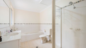 A bathroom with a bathtub, toilet, and shower area. - 3/54 Owen Street, Port Macquarie (Port Macquarie)