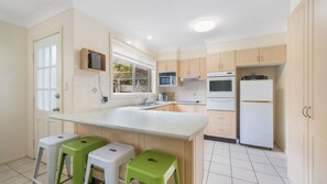 A modern kitchen with a large island, built-in appliances, and a window with a view.
