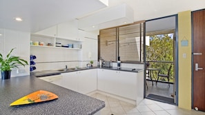 A modern kitchen with white cabinets, a granite countertop, and a built-in oven.