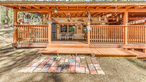 Eine Holzhütte mit Veranda, zwei Stühlen und einem kleinen Tisch.