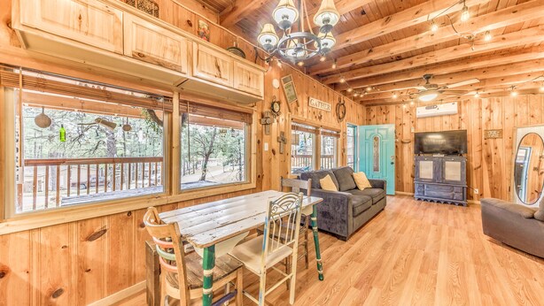 Ein Holzinterieur mit einem Esstisch, Stühlen, einer Couch und einem Fernseher.