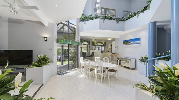 A modern interior with a dining area, kitchen, and a balcony with plants.