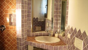 Une salle de bain équipée d’un lavabo, d’un miroir, de toilettes et d’un panier en osier.