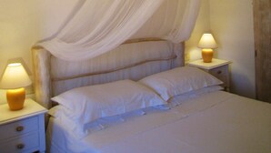 Un lit avec du linge de lit blanc, un baldaquin et deux lampes de chevet.
