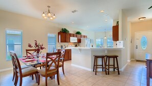 A modern kitchen with wooden cabinets, a central island, and bar stools. - 4-Bedroom Villa with Private Pool & Spa - near Disney & ChamionsGate (Davenport)