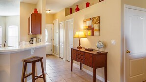 A kitchen with a bar area, wooden cabinets, a stool, and a desk with a lamp and globe. - 4-Bedroom Villa with Private Pool & Spa - near Disney & ChamionsGate (Davenport)