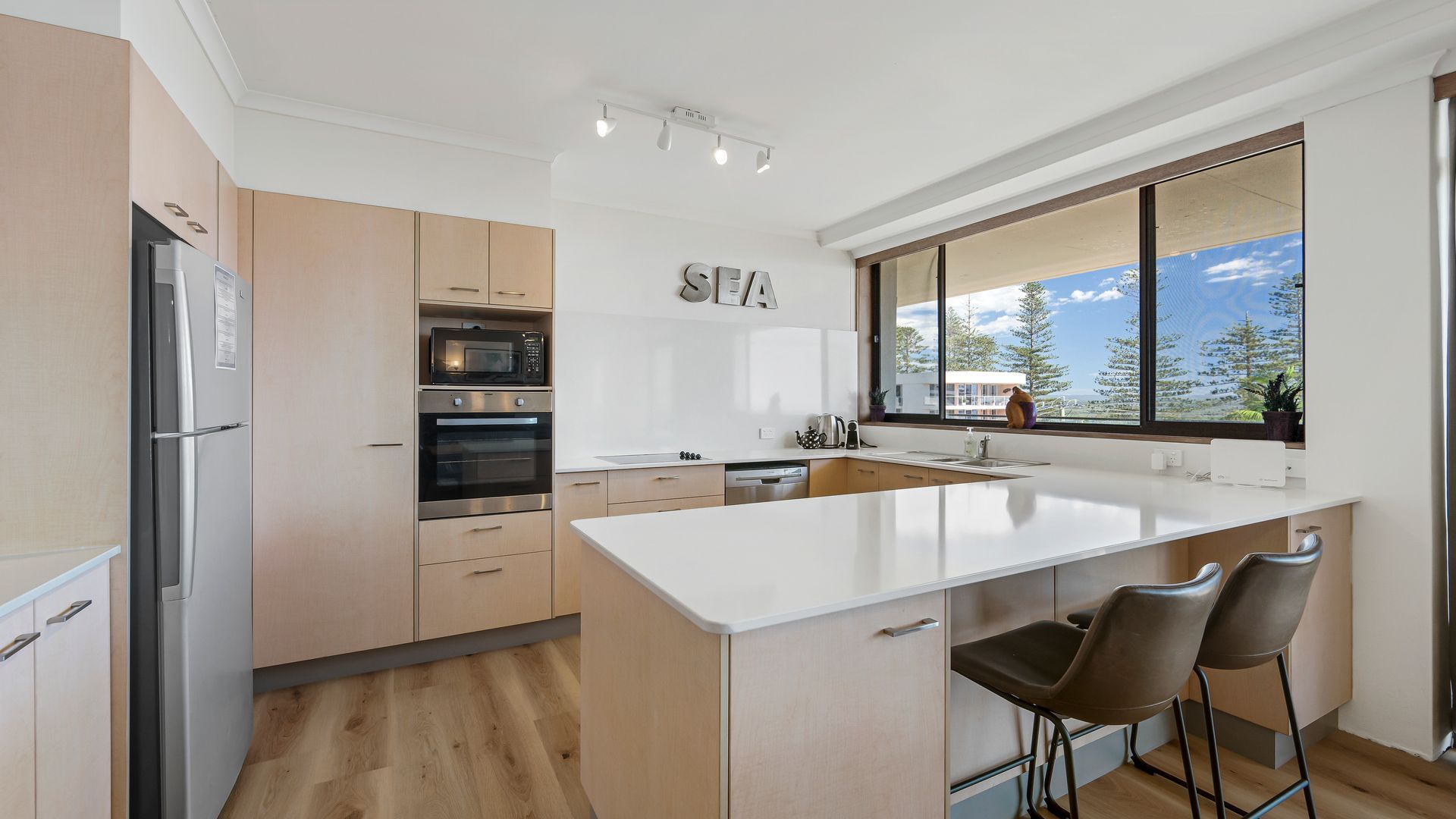 Una cocina moderna con una isla grande, electrodomésticos de acero inoxidable y vistas al exterior.