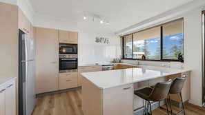 Una cucina moderna con una grande isola, elettrodomestici in acciaio inossidabile e vista sull'esterno.