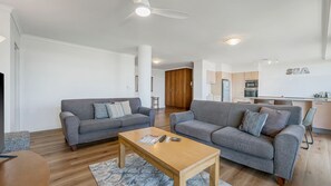 Una sala de estar moderna con dos sofás, una mesa de centro y una cocina al fondo.