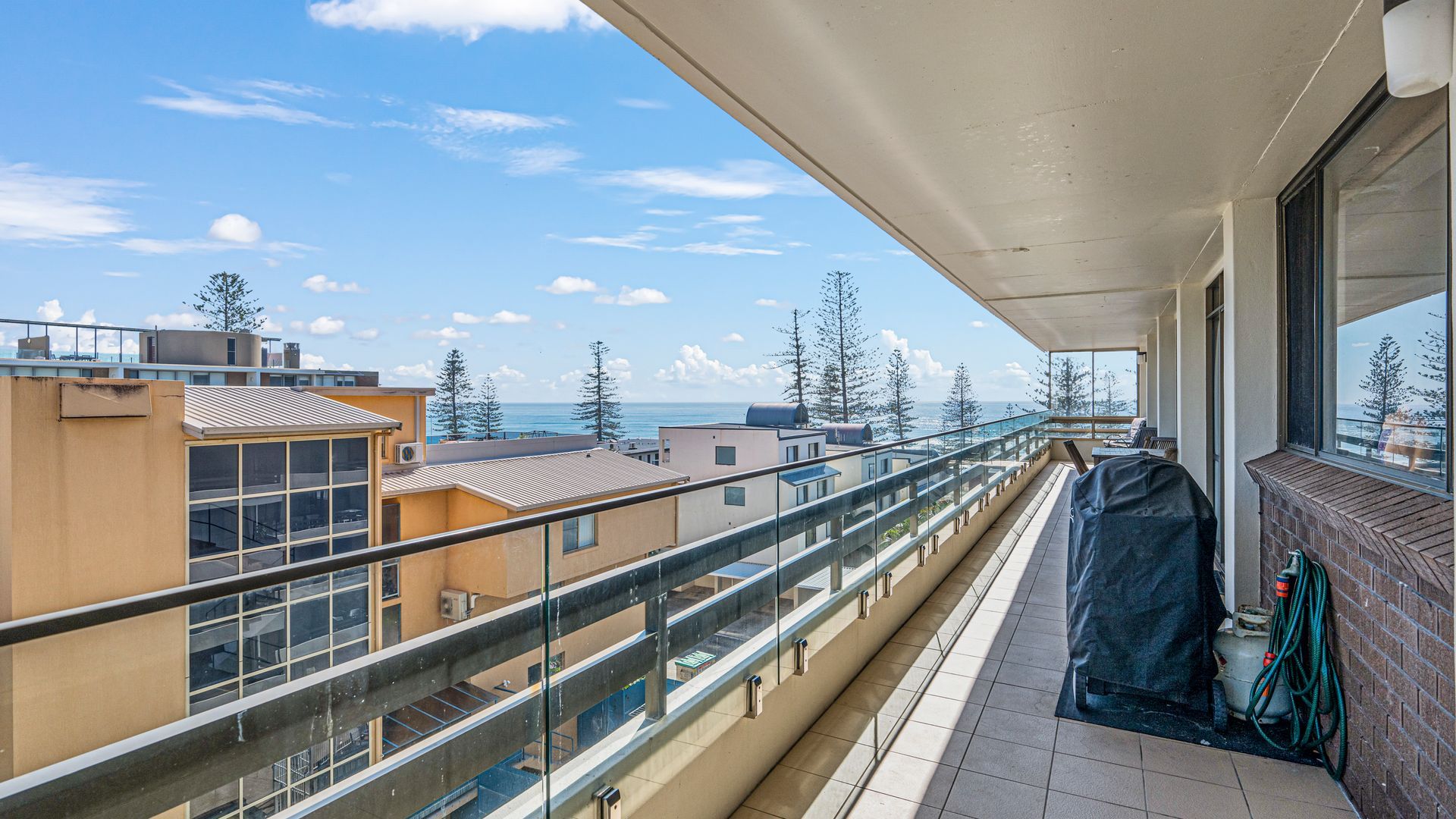 A balcony with a view of the sea and other buildings.