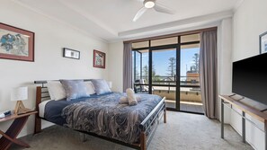 Camera d'albergo con letto, televisore, balcone e vista panoramica, e ventilatore a soffitto.