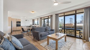 Un appartamento moderno con soggiorno, zona pranzo, angolo cottura e un balcone con vista.