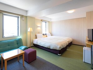 Una habitación de hotel con cama, sofá, mesa, televisión y ventana.