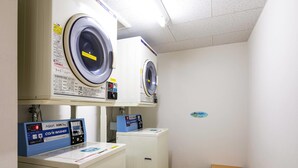 A laundry room with two front-loading washing machines and a coin-operated washer. - Comfort Inn Kashima (Kamisu)