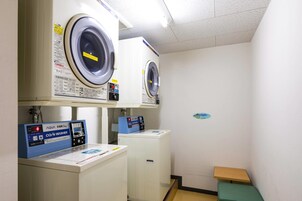 A laundry room with two front-loading washing machines and a coin-operated washer.