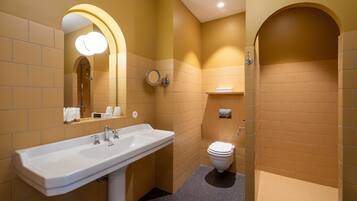 Un baño con un lavamanos blanco, un espejo con iluminación, un inodoro y un perchero para toallas.