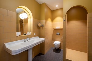 A bathroom with a white sink, a mirror with lights, a toilet, and a towel rack.
