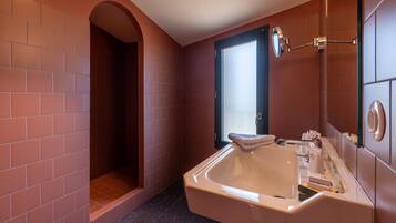 A bathroom with a large bathtub, a shower area, and a mirror.