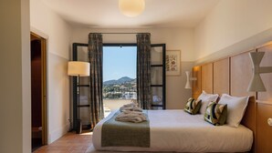 A hotel room with a large bed, a view of the city, and a balcony.