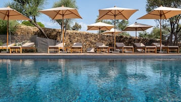 Una piscina al aire libre de temporada, sombrillas