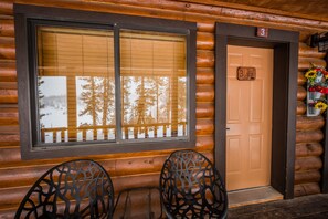 A log cabin with a large window, a door with a number, and two chairs outside. - Duck Creek Village Inn (Duck Creek Village)