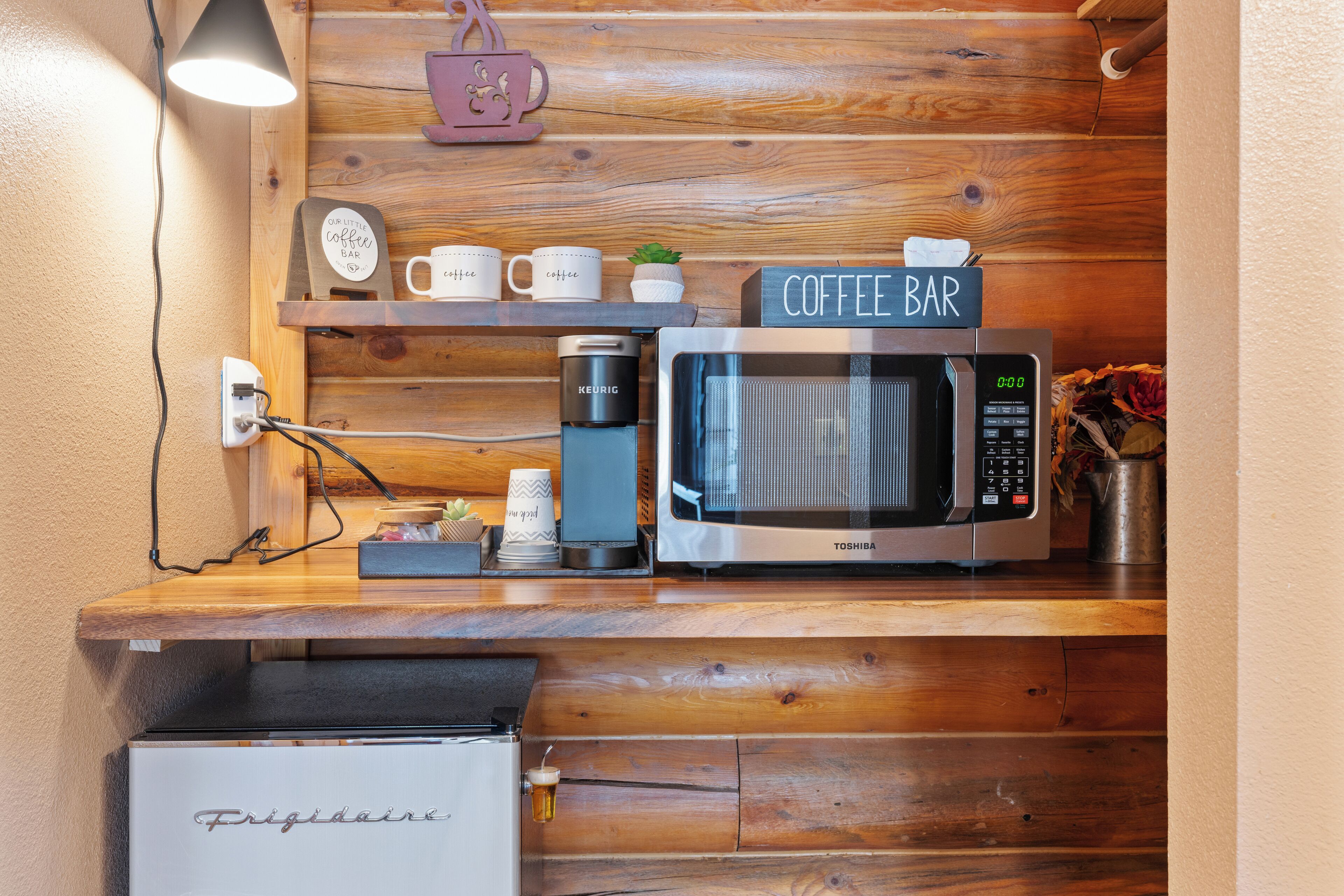 Un angolo cottura accessoriato con macchina del caffè, forno a microonde e frigorifero.